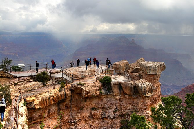 Walkers on the South Rim of the Grand Canyon under a breaking sky